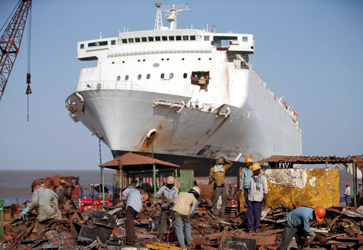 FILE PHOTO: Workers sort out scrap metal of a decommissioned ship at the Alang shipyard